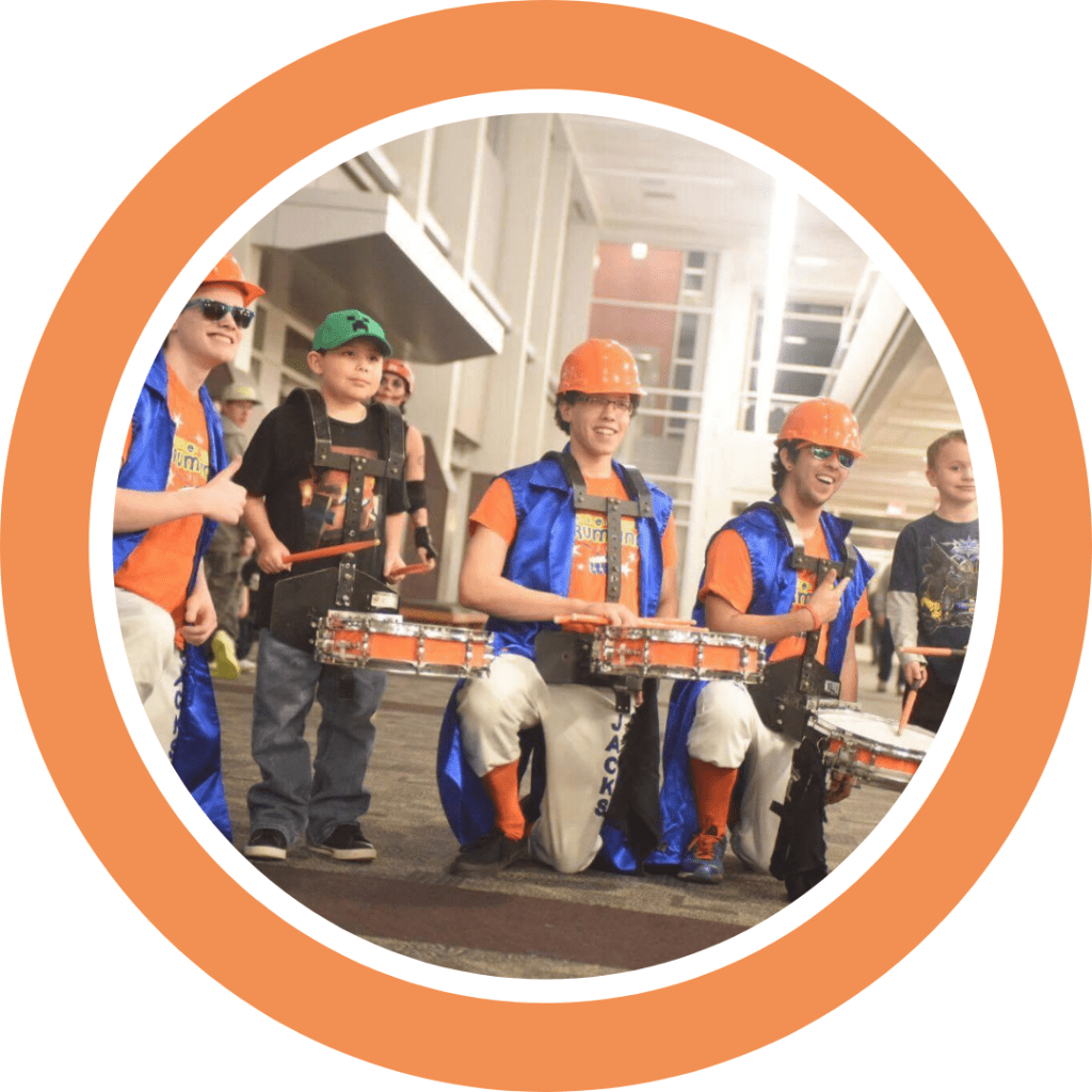 The Kracker Jacks Drumline posing with two kids wearing their drums